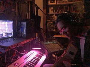 Man playing instrument in front of keyboard